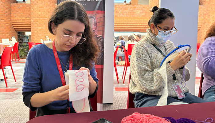 Integrantes de la comunidad universitaria bordan los nombres de mujeres víctimas de violencia feminicida, como parte de la jornada “Nombrarlas a todas” en la IBERO CDMX.